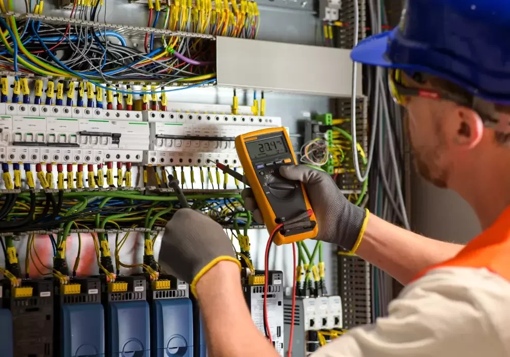 An electrician services a fuse box for a hotel's electrical system.