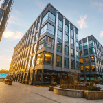 A large building towers against the setting sun. It looks like an office or apartment block.